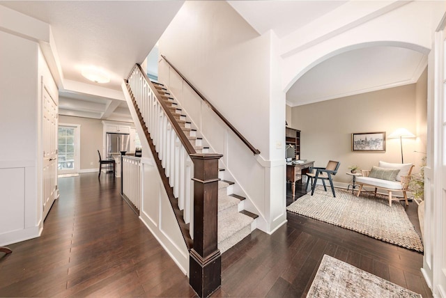 stairs featuring wood-type flooring, crown molding, arched walkways, and baseboards