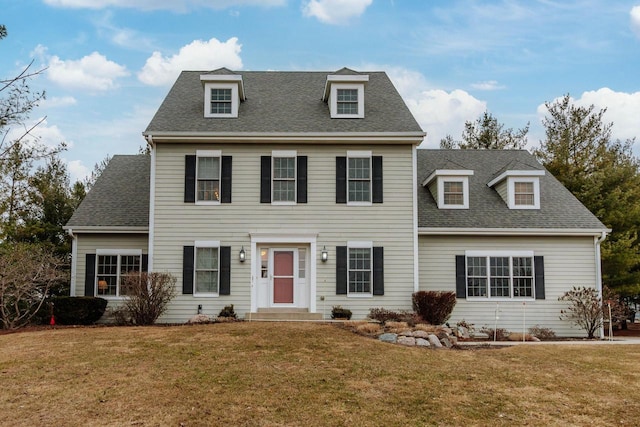 colonial inspired home with a front lawn and roof with shingles