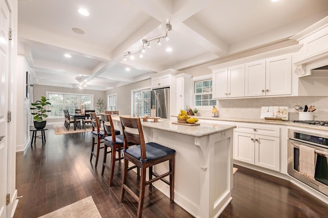 kitchen with appliances with stainless steel finishes, dark wood-style flooring, coffered ceiling, and a breakfast bar