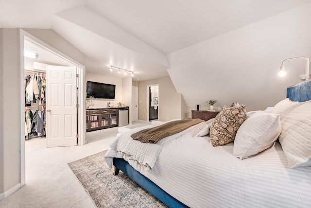 bedroom featuring baseboards, vaulted ceiling, a walk in closet, carpet floors, and a closet