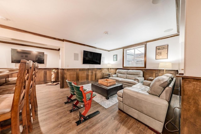 living room featuring a wainscoted wall, ornamental molding, and wood finished floors