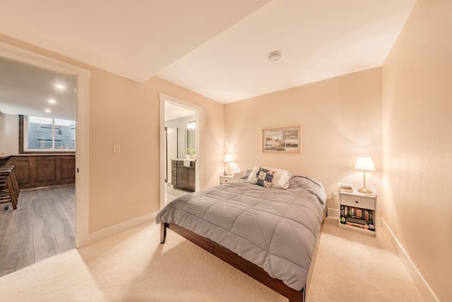 bedroom with light carpet, baseboards, and connected bathroom