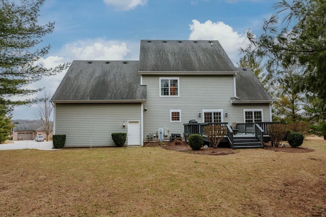 back of property with roof with shingles, a lawn, and a wooden deck