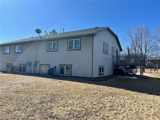 rear view of property featuring a lawn, central AC, and a wooden deck