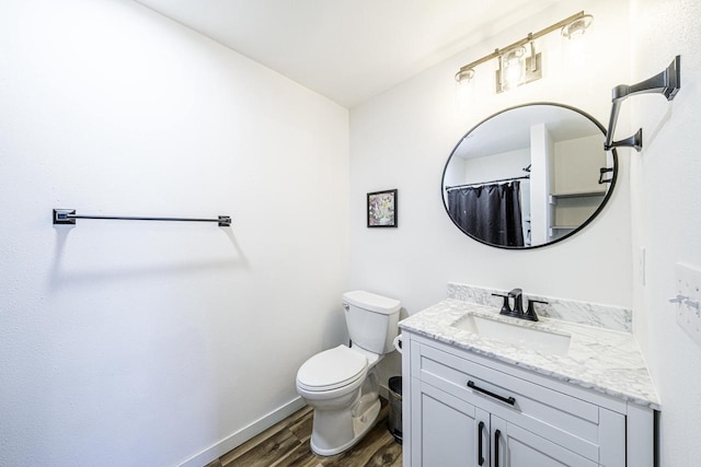 full bath with toilet, vanity, baseboards, and wood finished floors