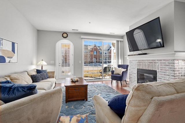 living area featuring a fireplace, visible vents, and wood finished floors