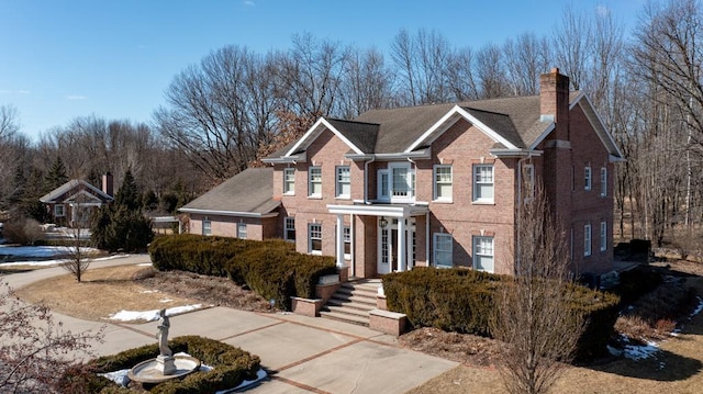 view of front of house featuring a chimney and brick siding