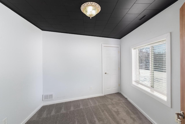 carpeted spare room featuring visible vents and baseboards