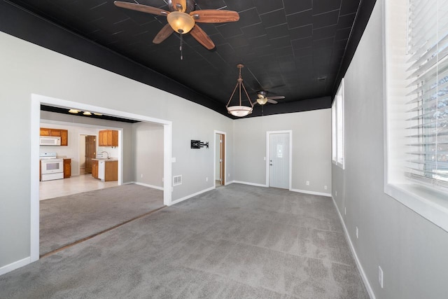 unfurnished room with ceiling fan, carpet, a sink, and baseboards