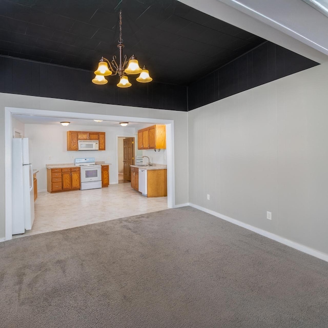 unfurnished living room featuring baseboards, a chandelier, a sink, and light colored carpet