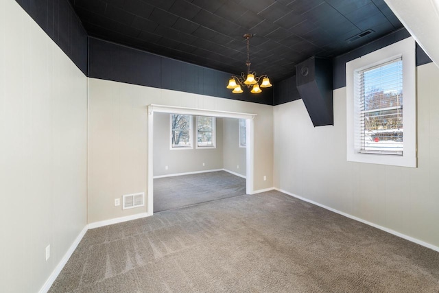 unfurnished room featuring carpet, visible vents, a chandelier, and baseboards