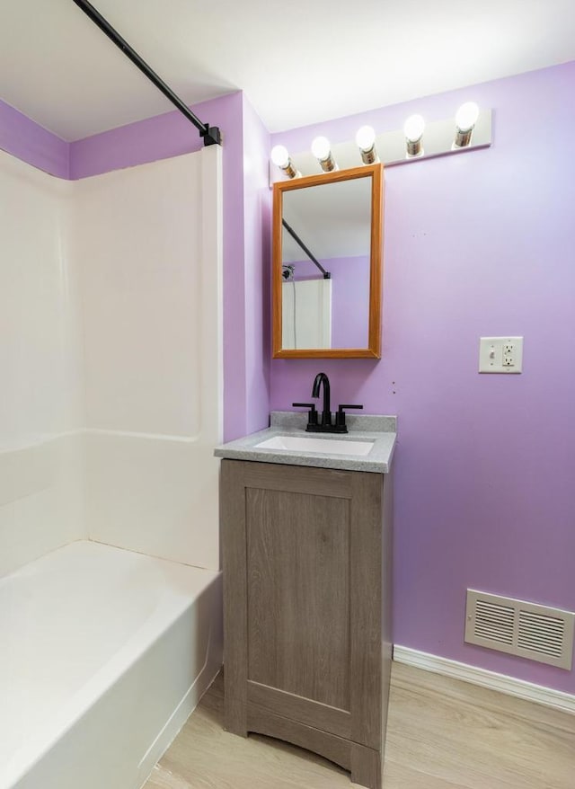 full bath featuring shower / bath combination, visible vents, vanity, and wood finished floors