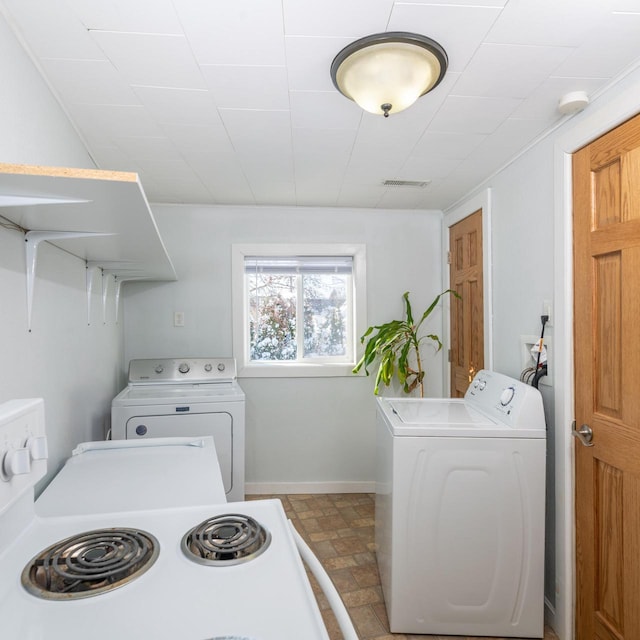 washroom featuring washing machine and dryer, visible vents, and baseboards