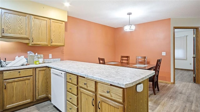 kitchen featuring a peninsula, light wood finished floors, light countertops, and dishwasher