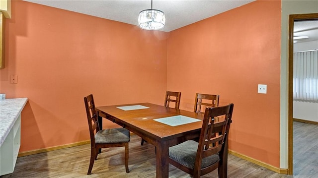 dining area with an inviting chandelier, wood finished floors, and baseboards