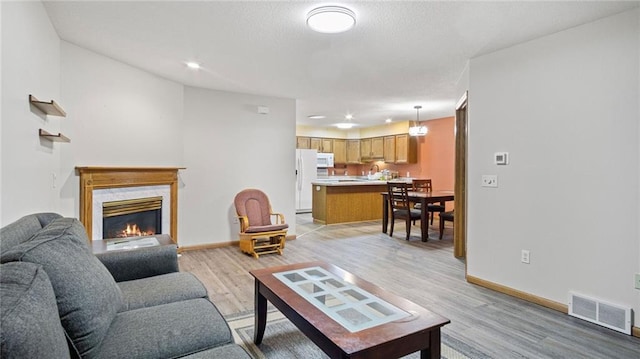 living area featuring light wood finished floors, baseboards, a fireplace, and visible vents