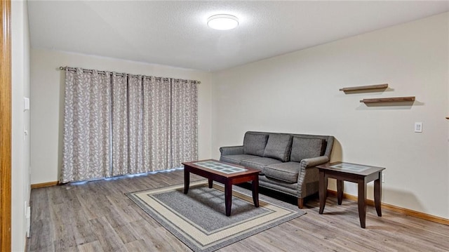 sitting room with a textured ceiling, wood finished floors, and baseboards