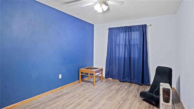 spare room featuring a textured ceiling, wood finished floors, a ceiling fan, and baseboards