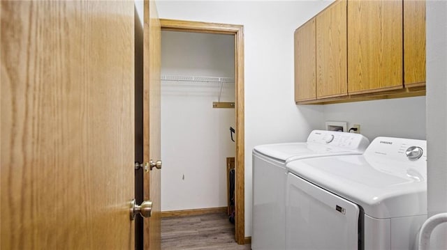 laundry area featuring separate washer and dryer, light wood-style flooring, cabinet space, and baseboards