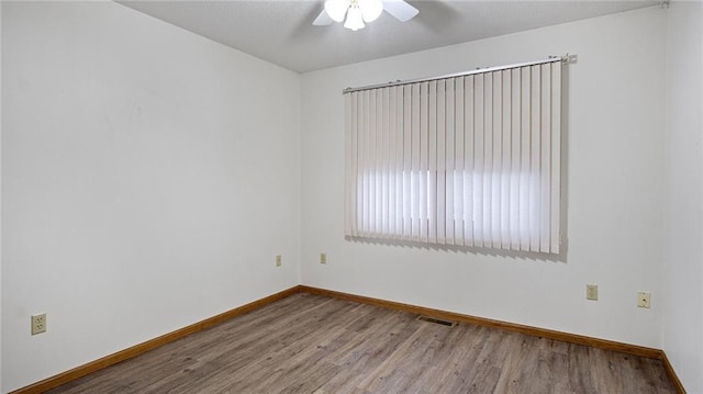 unfurnished room featuring a ceiling fan, wood finished floors, visible vents, and baseboards