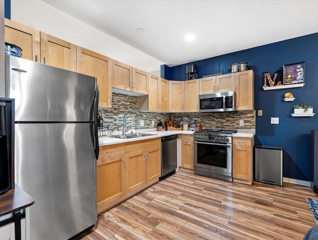 kitchen featuring light wood finished floors, light countertops, light brown cabinetry, appliances with stainless steel finishes, and a sink