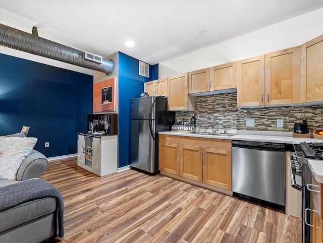 kitchen featuring stainless steel appliances, light countertops, a sink, and light wood finished floors