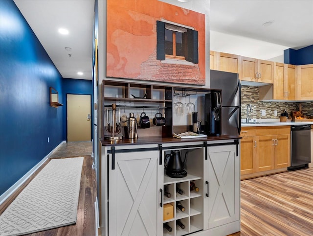 kitchen with backsplash, light wood-style floors, light brown cabinets, a sink, and dishwasher