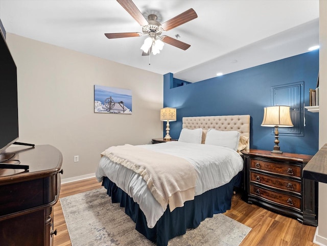 bedroom featuring ceiling fan, baseboards, and wood finished floors