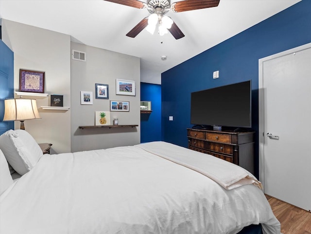 bedroom featuring ceiling fan, wood finished floors, and visible vents