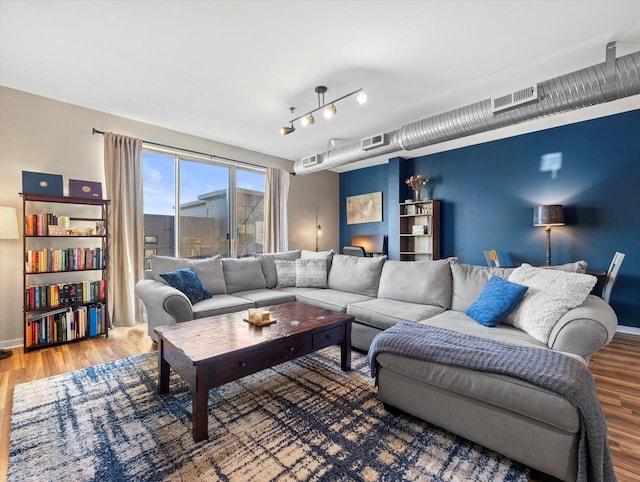 living room with wood finished floors, visible vents, and rail lighting