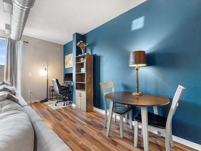 dining space with baseboards and wood finished floors