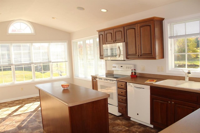 kitchen with recessed lighting, white appliances, a sink, vaulted ceiling, and plenty of natural light