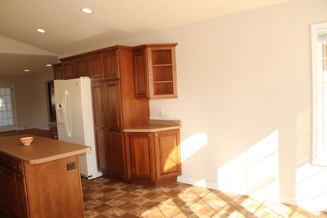 kitchen with brown cabinetry, recessed lighting, white refrigerator with ice dispenser, and light countertops