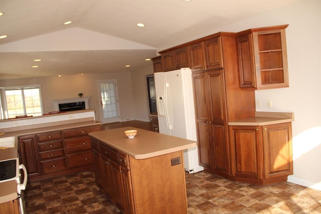 kitchen featuring lofted ceiling, a kitchen island, light countertops, white fridge with ice dispenser, and a high end fireplace