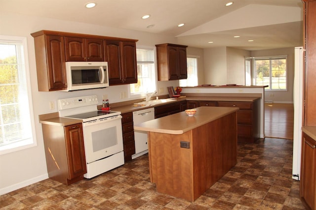 kitchen featuring a peninsula, white appliances, plenty of natural light, and a sink