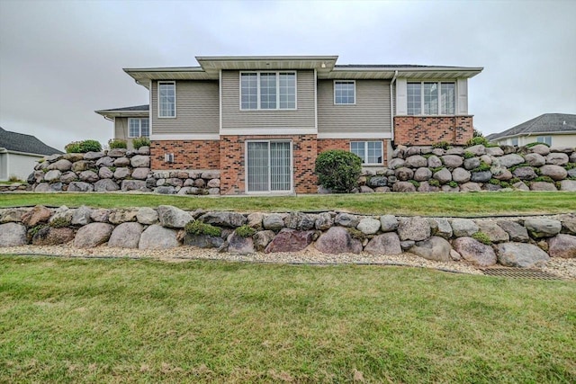 back of house featuring brick siding and a yard