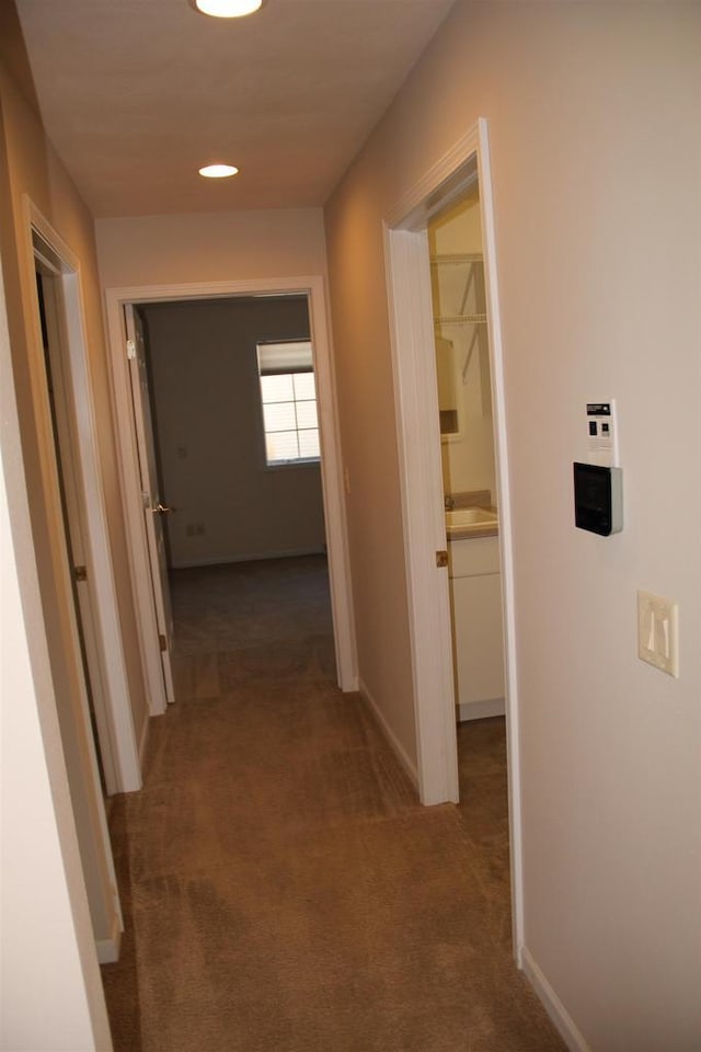 hallway featuring carpet floors and baseboards