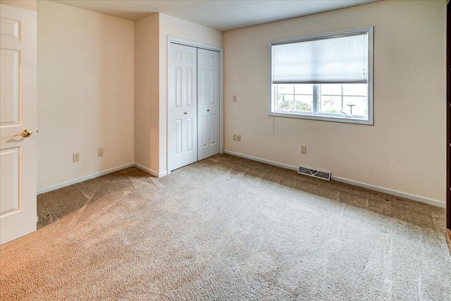 unfurnished bedroom with baseboards, a closet, visible vents, and light colored carpet