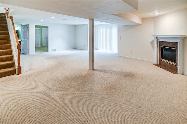 finished basement featuring carpet, recessed lighting, baseboards, stairway, and a tiled fireplace