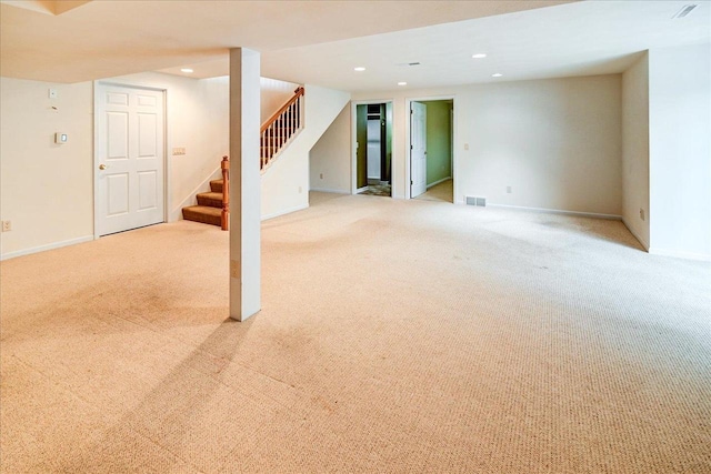 finished below grade area featuring stairs, baseboards, light colored carpet, and recessed lighting