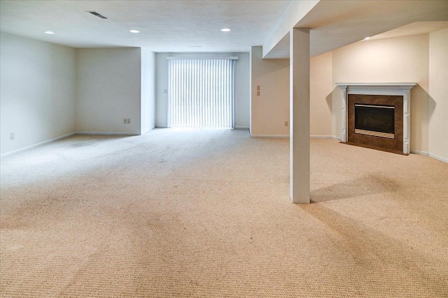 below grade area featuring visible vents, baseboards, a fireplace with flush hearth, carpet, and recessed lighting