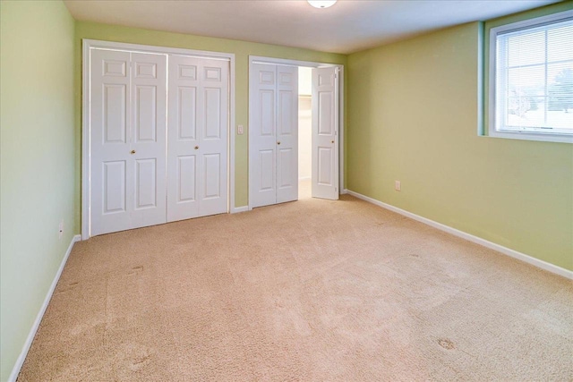 unfurnished bedroom featuring baseboards, carpet flooring, and multiple closets