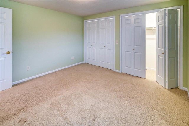 unfurnished bedroom featuring multiple closets, carpet, and baseboards