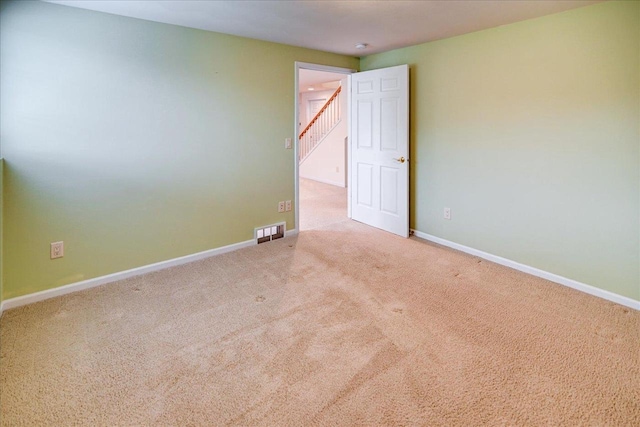 carpeted spare room with visible vents and baseboards