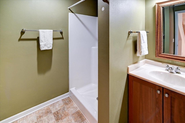 full bathroom featuring baseboards, a walk in shower, and vanity