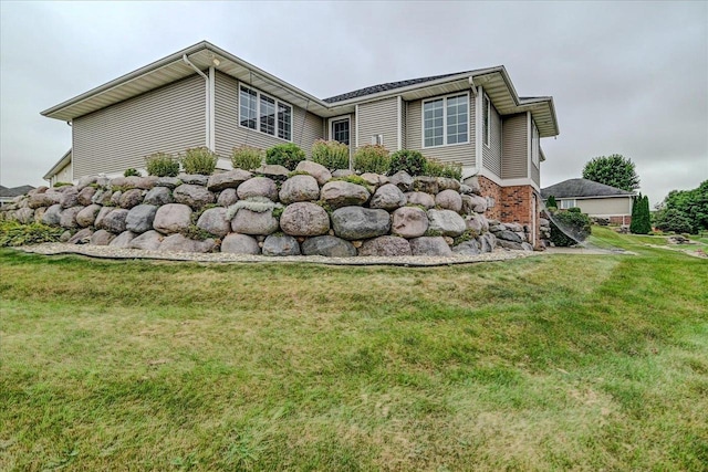 view of side of property with brick siding and a yard