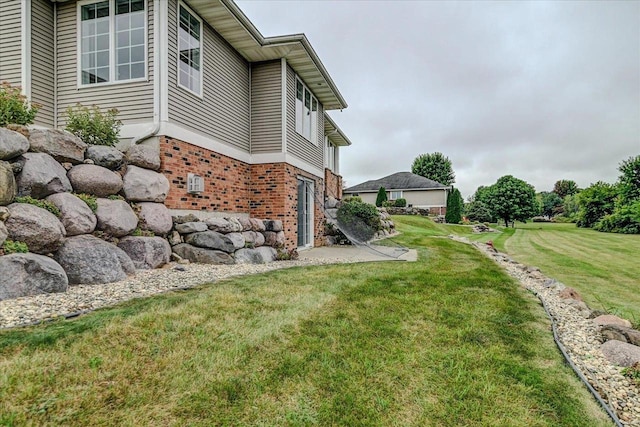 view of property exterior featuring brick siding and a lawn