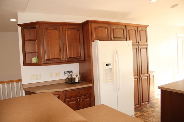 kitchen featuring white fridge with ice dispenser, recessed lighting, brown cabinetry, and light countertops