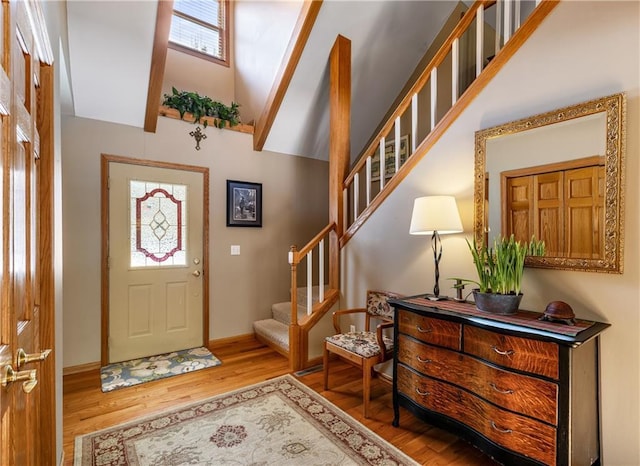 foyer featuring stairs, vaulted ceiling, wood finished floors, and baseboards