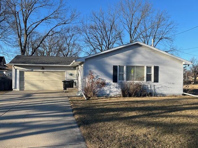 view of front facade featuring concrete driveway, a front lawn, and an attached garage